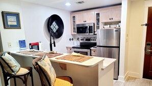 Une cuisine moderne dotée d’un îlot central, de chaises en bois et d’appareils électroménagers en acier inoxydable.