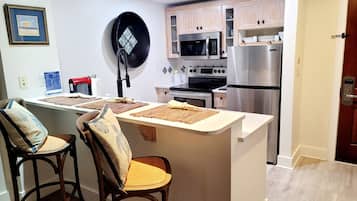 Een moderne keuken met een centraal eiland, houten stoelen en roestvrijstalen apparatuur.