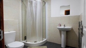 Kylpyhuoneessa on lasiseinällä varustettu suihku, wc ja jalkapallin muotoinen pesuallas.