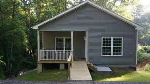 A small, single-story cabin with a porch and a wooden deck.