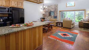 Una cocina amplia con armarios de madera, encimera de granito y pared de acento de piedra.