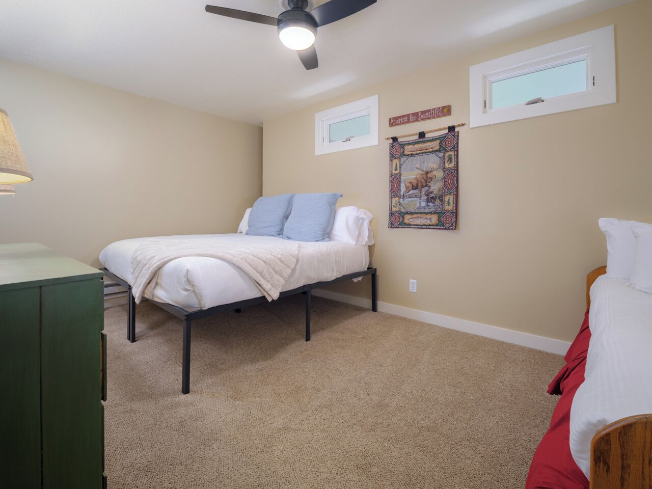 A bedroom with a bed, a ceiling fan, a window, and a wall tapestry.