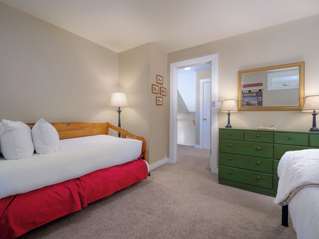 Une chambre à coucher avec un lit, une commode verte et une porte donnant sur une autre pièce.