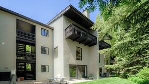 Un edificio moderno de dos pisos con un balcón, un patio cubierto y un césped bien cuidado.