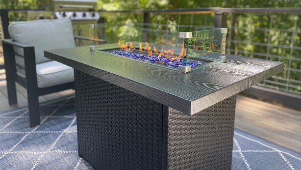 Un área de estar moderna al aire libre con chimenea integrada y cerramiento de vidrio.