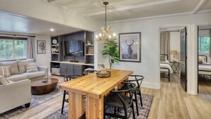 Un salón amplio con una mesa de comedor de madera, un sofá y un televisor al fondo.