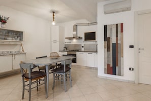 A modern kitchen with white cabinets, a dining table with chairs, and a decorative wall piece.