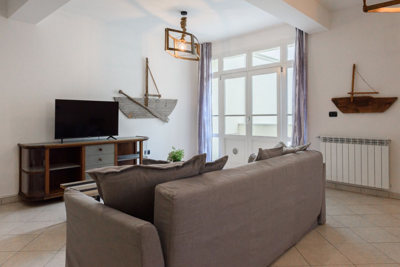 A living room with a sofa, TV, wooden decor, and a window with curtains.