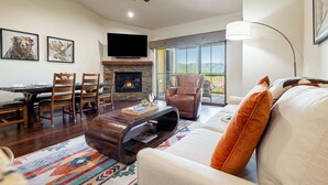 A living room with a fireplace, a ceiling fan, a TV, and a large window offering a view. - Close to World-class Ski Resorts  and Summer Activities on the Lake (Heber City)