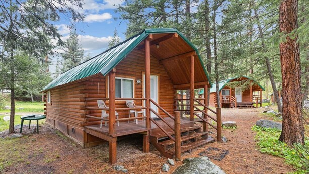 Eine rustikale Holzhütte mit Veranda, einer Holzterrasse und einem kleinen Tisch.