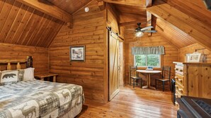 Ein gemütliches Schlafzimmer in einer Blockhütte mit Bett, Schreibtisch und Stuhl.
