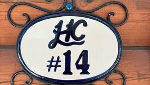 A house number sign with a decorative metal frame and a white background.