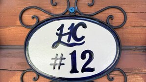 A house number sign with the letters "HC" and the number "12" on a white background, surrounded by a decorative metal frame. - Log Cabin Retreat in the Montana Wilderness (Hamilton)