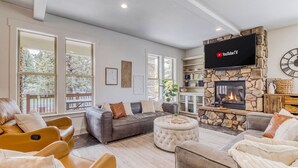 Un salon moderne avec une cheminée en pierre, des canapés en cuir et un téléviseur à écran plat fixé au-dessus de la cheminée.