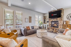 Een moderne woonkamer met een stenen openhaard, leren banken en een flatscreen televisie erboven.