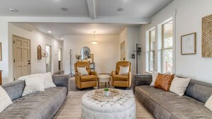 Un salon moderne avec deux canapés, un pouf rond et une petite table avec des chaises.