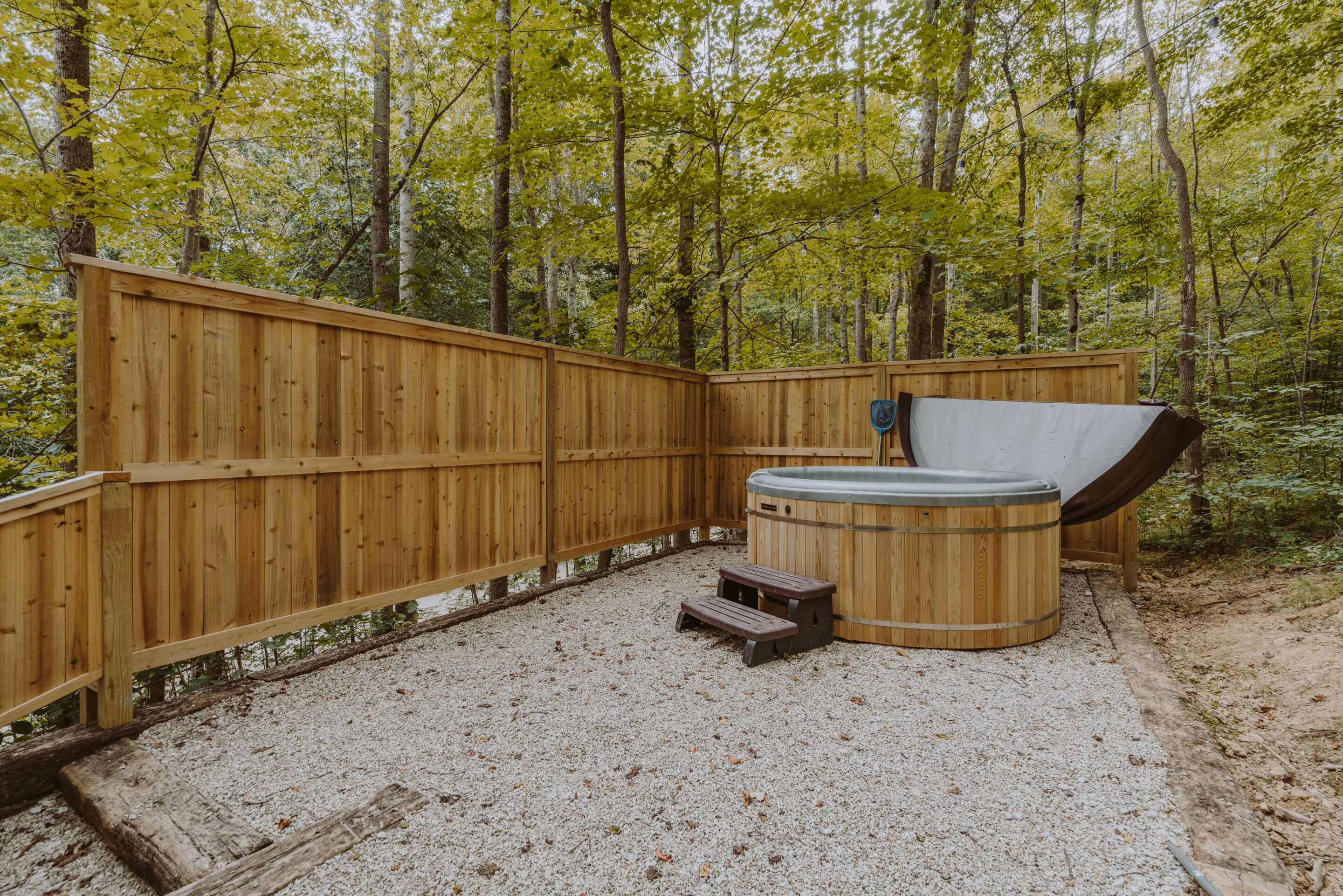 Eine Holzterrasse mit Whirlpool und einer kleinen Holzbank.
