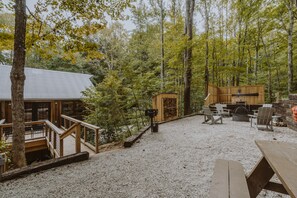 Eine rustikale Holzhütte mit einer Terrasse, einer Feuerstelle und Sitzgelegenheiten im Freien.