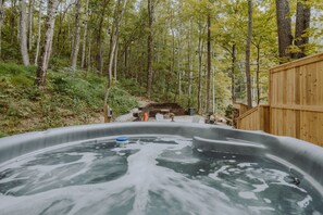 Ein Whirlpool, umgeben von einer Holzterrasse und einem bewaldeten Gebiet.