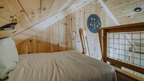 Ein Holzhütten-Zimmer mit einem Bett, einer runden Wanddekoration und einem Fenster mit Gitter.