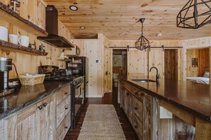 Ein Holzhütten-Innenraum mit einer Küchenzeile, die einen Herd, ein Spülbecken und Holzschränke beinhaltet.