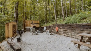 Ein rustikaler Außenbereich mit Holzstühlen und einem Tisch, umgeben von einer Holzterrasse und einer Steinmauer.