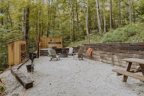 Ein rustikaler Außenbereich mit Holzstühlen und einem Tisch, umgeben von einer Holzterrasse und einer Steinmauer.