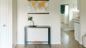 A hallway with a world map on the wall, a console table with a plant, and a view into another room.