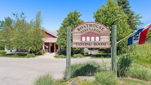 A wooden sign for Boathouse Vineyards Tasting Room with a stone building in the background.