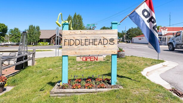 Un letrero de madera con la palabra 'Fiddleheads' y 'ABIERTO', indicando que el negocio está funcionando.