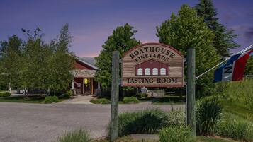 A wooden sign for Boathouse Vineyards Tasting Room with a stone building in the background.