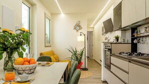 Una cocina moderna con comedor, que incluye una mesa para el desayuno con naranjas y un jarrón de flores.
