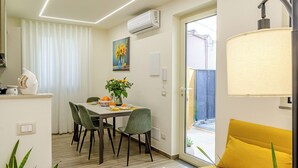 Un comedor moderno con una mesa dispuesta para dos personas, un sofá amarillo y vistas al exterior.