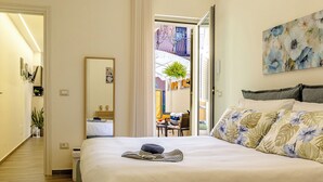 Una habitación de hotel con una cama grande, un espejo, un cuadro y vistas al balcón exterior.