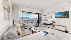 Moderni hotellihuone, jossa on parveke, sohva, ruokapöytä ja sänky.