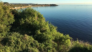 A coastal landscape with a clear view of the sea and a distant shoreline with buildings. - Quiet, luxurious Guest House - Couples Retreat (Mornington)