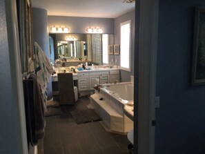 A modern bathroom with a large mirror, vanity, bathtub, and a shower area.