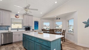 A spacious kitchen with a large island, white ceiling, and wooden flooring. - Waves of Joy: Oceanside, Private Heated Pool, Hot Tub (Nags Head)