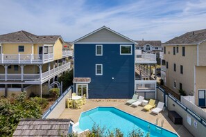 Ein Wohngebäude mit Schwimmbad, Sitzgelegenheiten im Freien und einem Balkon.