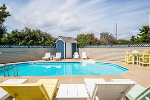 En swimmingpool med liggestole og et lille skur.