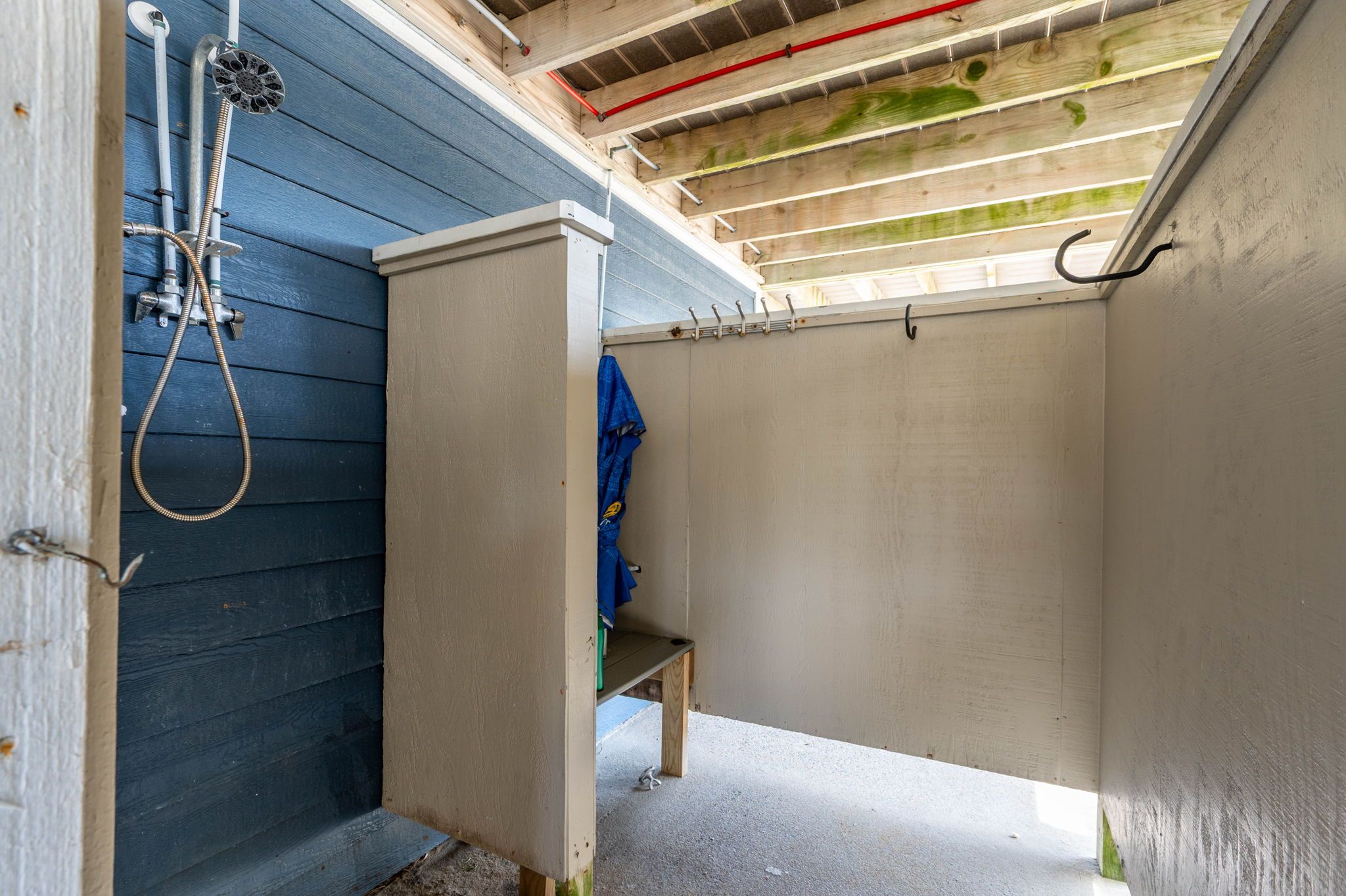 A small, enclosed shower area with a wooden ceiling and a bench.