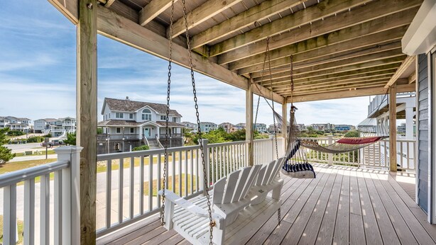 A wooden deck with a swing and hammock, overlooking a residential area. - Waves of Joy: Oceanside, Private Heated Pool, Hot Tub (Nags Head)