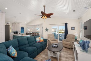Ein großzügiger Wohnbereich mit Deckenventilator, einer Couch, einem Couchtisch und Blick ins Freie.