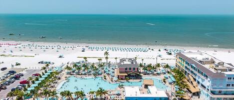 A resort with a large pool, beach area, and multiple buildings.