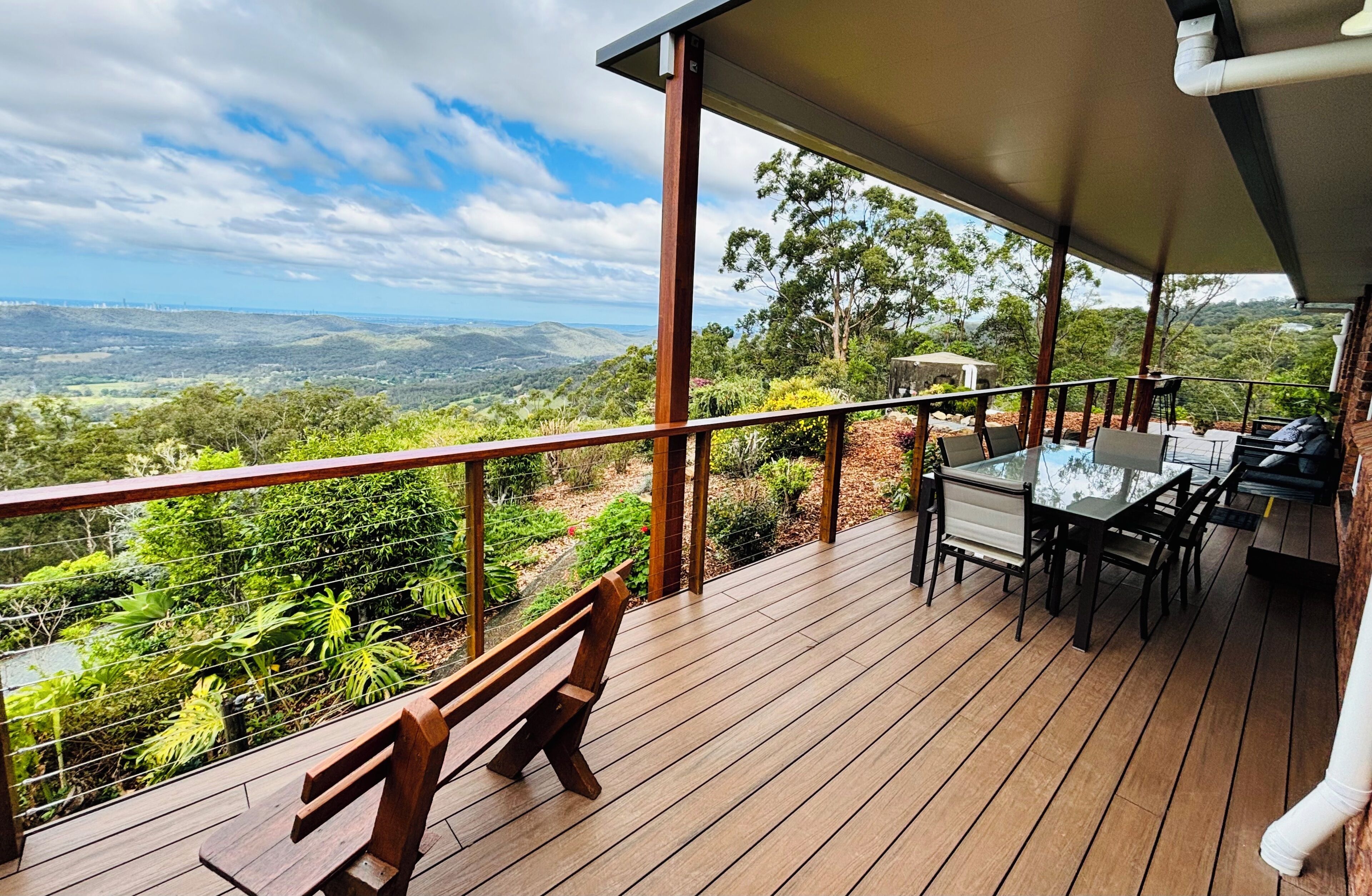 Una terraza de madera con una mesa y sillas, con vista a un paisaje montañoso.
