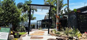 A sign welcoming guests to The Hillside Retreat with a pathway leading to a building.