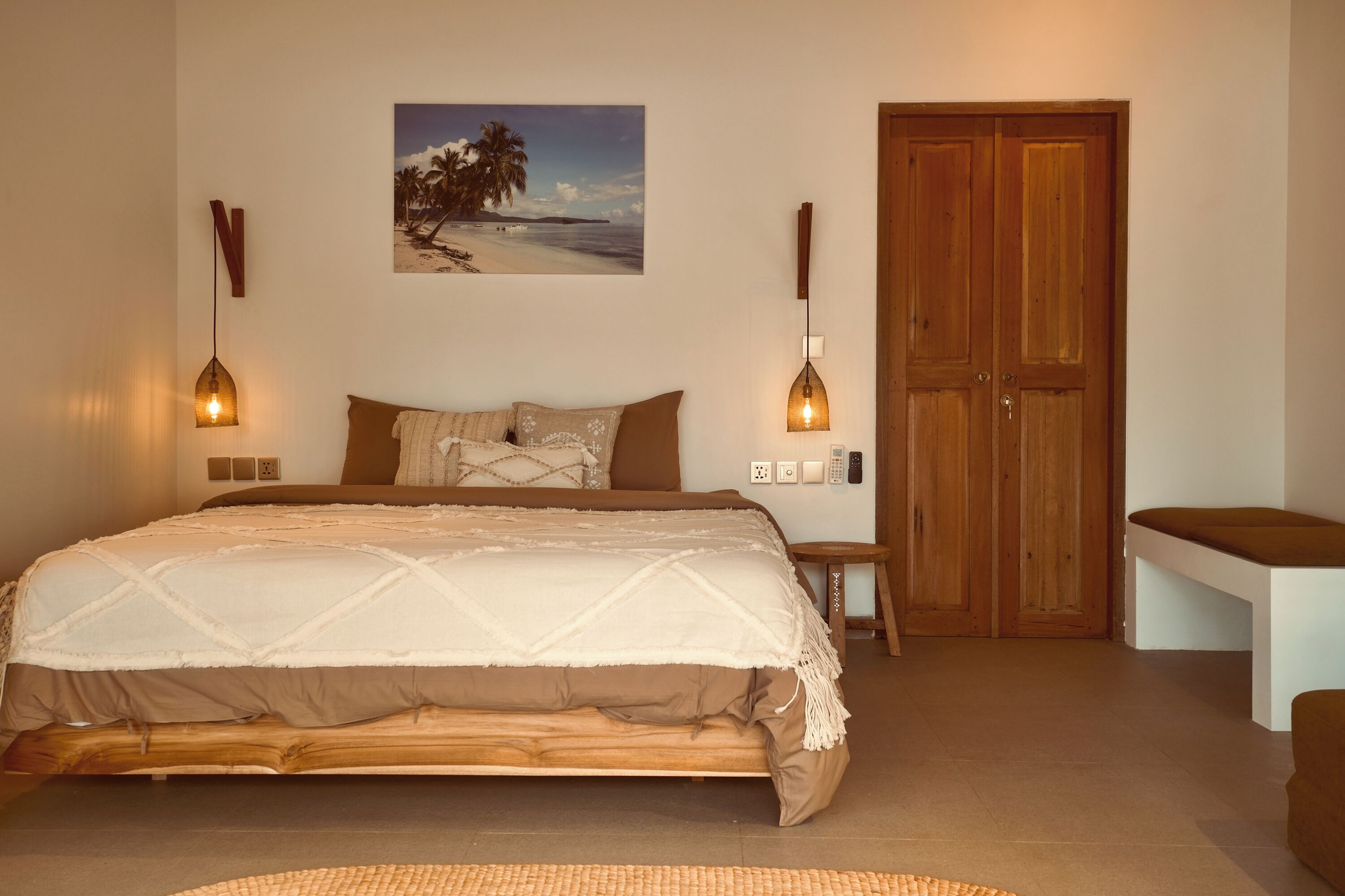 Ein Schlafzimmer mit einem großen Bett, einer Holztür, einer Bank und einem Wandbild.