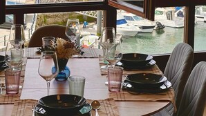A dining area with a view of a marina and buildings.