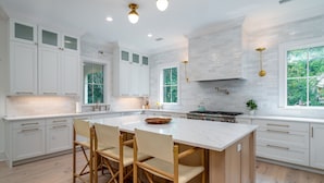A spacious kitchen with white cabinetry, a large island with bar stools, and a view of greenery outside. - Fabulous 5 BR/5.5 BA Home! New Construction! Pool! Screen Porch! Amenity access included (Seabrook Island)