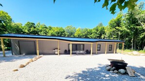 A covered outdoor area with a gravel floor, a fire pit, and a table and chairs. - Barndominium on H-58 near Pictured Rocks Attractions 
 (Shingleton)